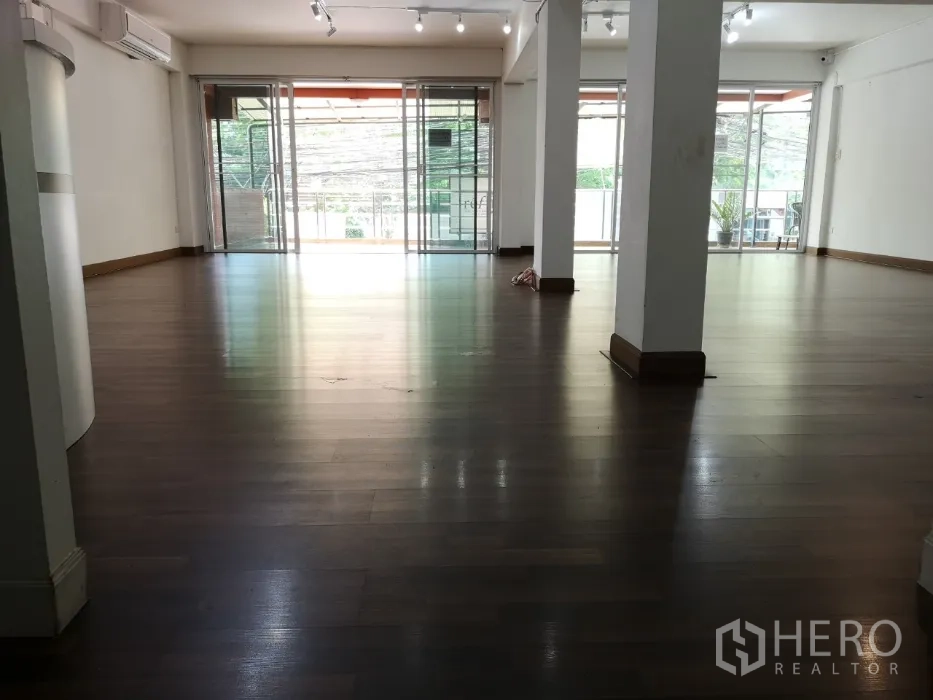 Office Space for rent in Khlong Toei, Bangkok - Spacious office area with support columns and glass doors opening to a balcony.
