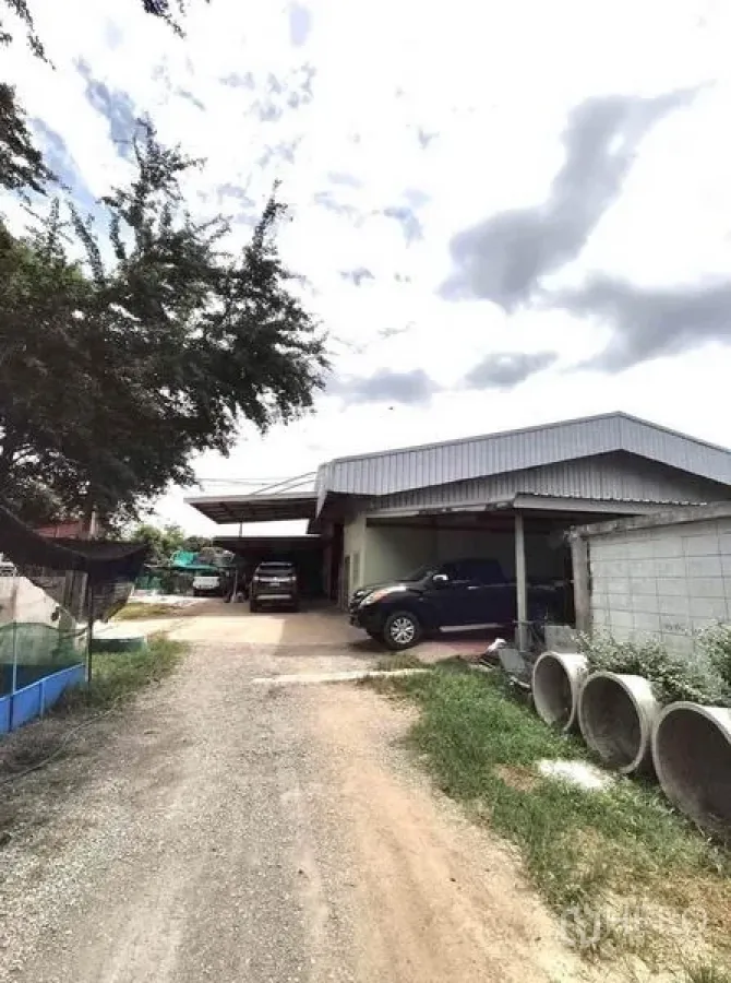 โรงงาน ขายในLat Lum Kaeo, Pathum Thani - ภายนอกโรงงานหลังคาเมทัลชีท ทางรถลูกรัง กำแพงรั้ว และที่จอดรถในบรรยากาศครึ้มฟ้า ลาดหลุมแก้ว