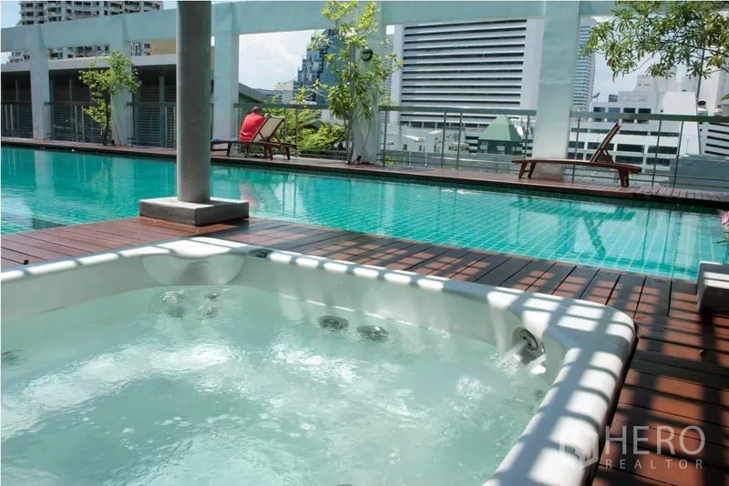 Apartment for rent in Bang Rak, Bangkok - Rooftop swimming pool and jacuzzi on a wooden deck with Bangkok skyline views.