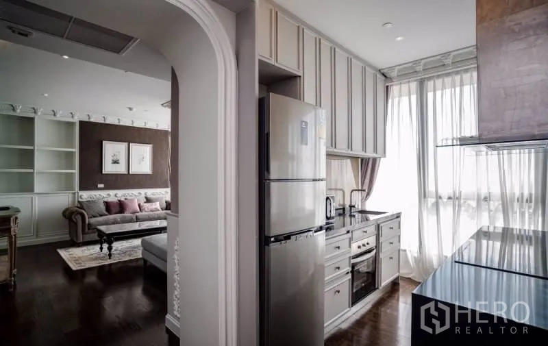 Condominium for rent or sale in Khlong Toei, Bangkok - Compact separate kitchen with full-height cabinets, built-in oven and large windows beside the living area.