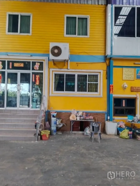 Warehouse for sale in Sai Noi, Nonthaburi - Front of warehouse office showing staircase, air-conditioning unit, and windows.