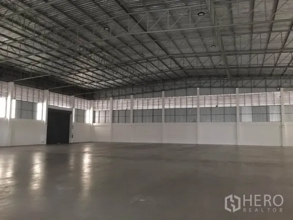 工厂 出租在Samut Prakan - 宽敞仓库内部，高挑无柱钢桁架屋顶，光滑混凝土地面与通风墙体。