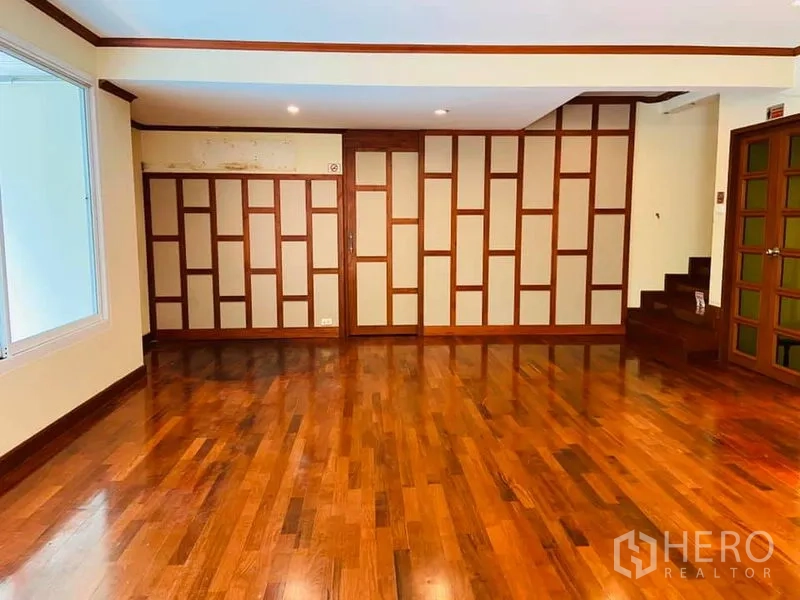 บ้าน ให้เช่าในKhlong Toei, Bangkok - ห้องโล่งพื้นไม้ ผนังลายไม้และบันไดภายในบ้าน