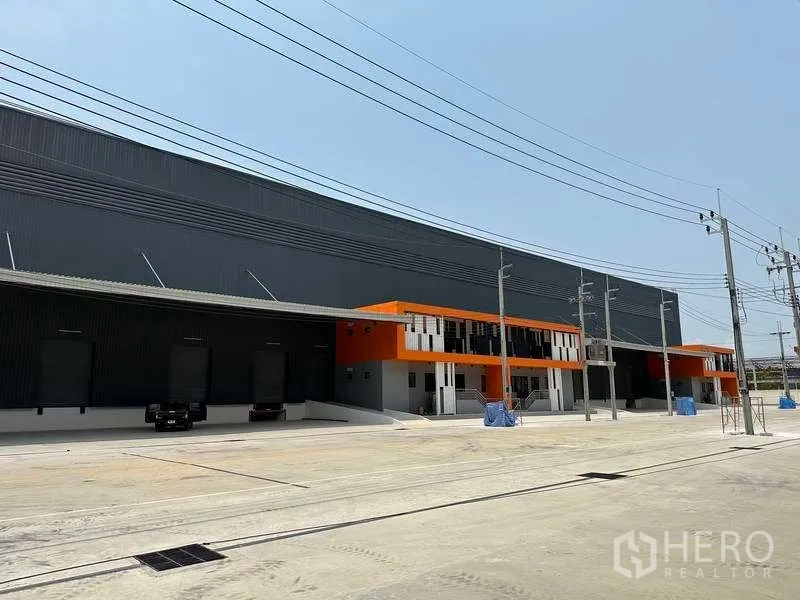 工厂 出租在Bang Phli, Samut Prakan - 邦普里自由区工厂外观，橙色点缀办公室，多个高位装卸月台与宽阔车场。
