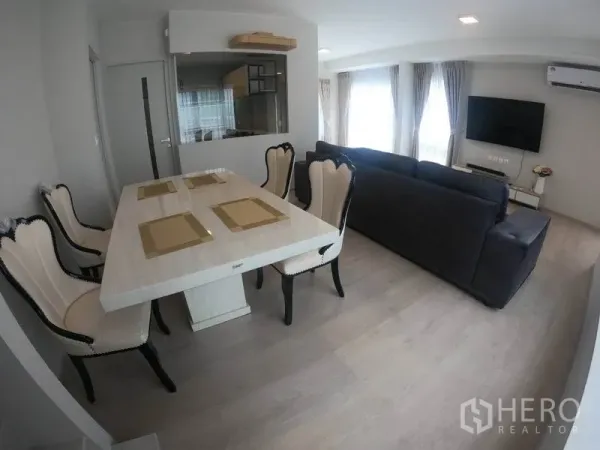 Detached House for rent in Prawet, Bangkok - Dining area with marble-style table and upholstered chairs beside the living room.