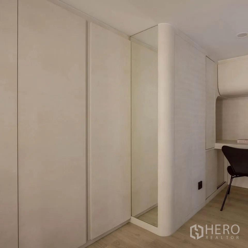 Condominium for rent in Khlong Toei, Bangkok - Bedroom corner with beige wardrobes, full-height mirror, and study desk.