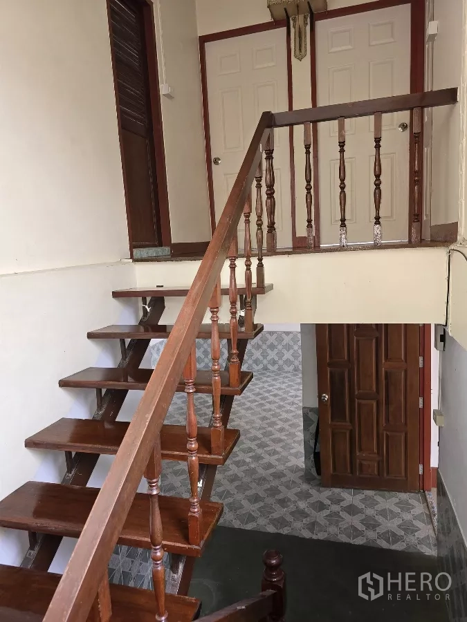 Home Office for rent in Wang Thonglang, Bangkok - Wooden staircase with turned handrails leading to an upper landing and paneled doors.