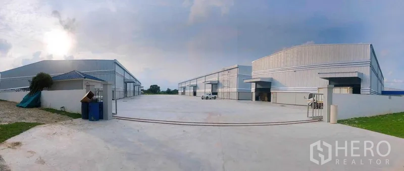 Warehouse for rent in Ban Bueng, Chon Buri - Panoramic view of multiple modern warehouse buildings with a wide concrete yard for truck maneuvering.