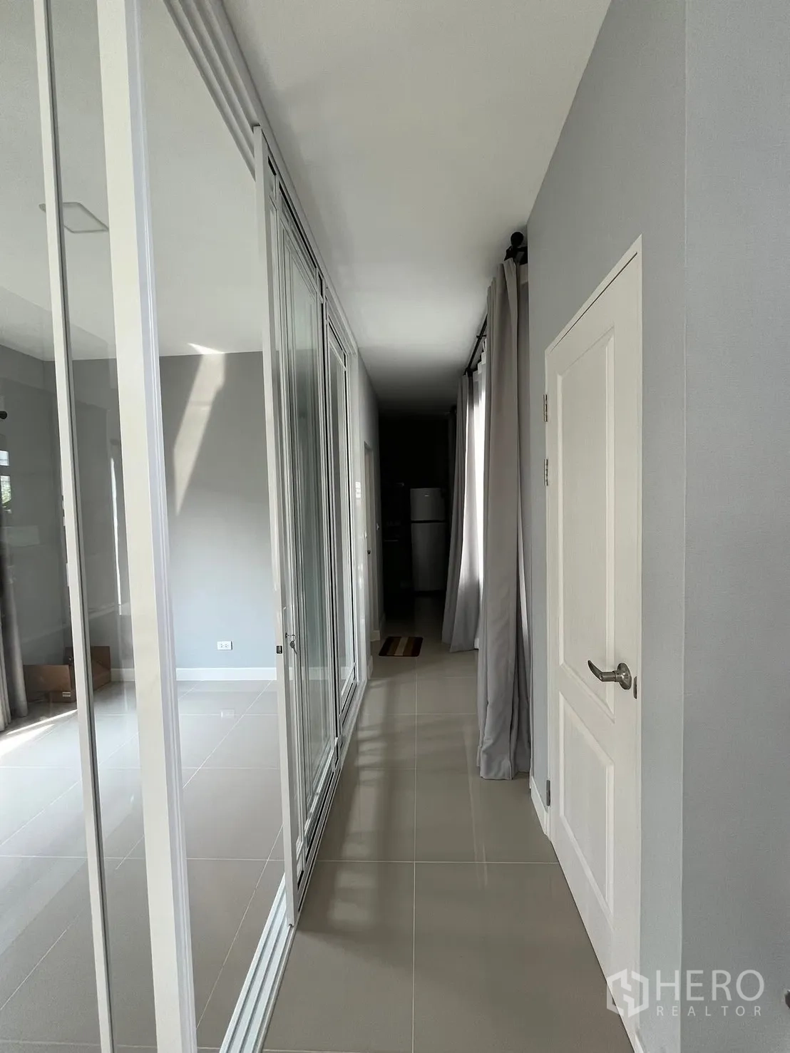 Detached House for rent in Bang Phli, Samut Prakan - Hallway with glossy floor tiles and full-height glass partitions leading to living area.