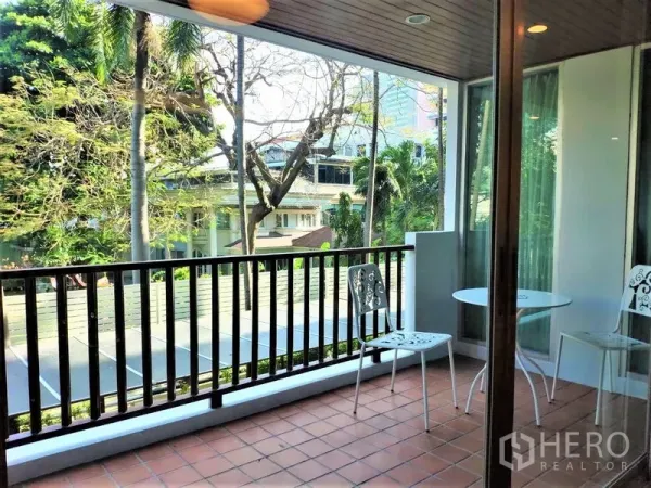 Condominium for rent in Bang Rak, Bangkok - Covered balcony with terracotta tiles, bistro chairs and leafy treetop views.