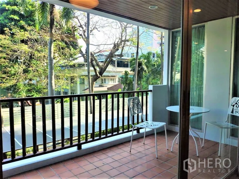 Condominium for rent in Bang Rak, Bangkok - Covered balcony with terracotta tiles, bistro chairs and leafy treetop views.