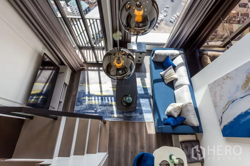 公寓 出租或出售在Chatuchak, Bangkok - 从夹层俯视客厅与整面落地窗、阳台及蓝色软装