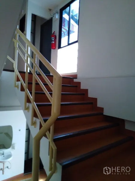 Office Space for sale in Bang Kapi, Bangkok - Internal staircase with natural light from a window and metal handrail.