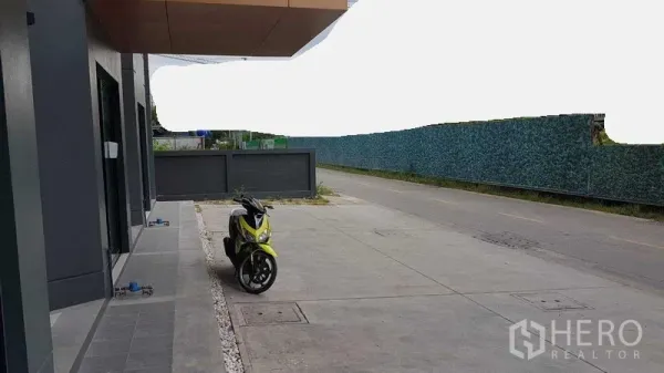 店屋 出租或出售在Bang Na, Bangkok - 店面前方宽阔混凝土前庭与推拉门，临安静小路。