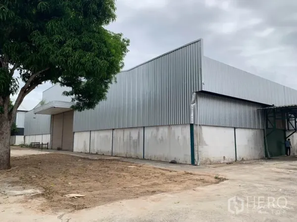 工厂 出租在Chon Buri - 春武里Phanat Nikhom钢结构工厂外观，卷闸门与混凝土场地。