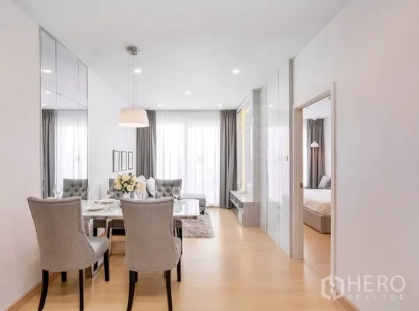 Condominium for sale in Yan Nawa, Bangkok - Open-plan living zone with dining set, large windows and a doorway leading to the bedroom.