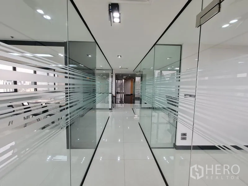 办公空间 出租在Bang Rak, Bangkok - 简洁走廊，磨砂条纹玻璃隔断与洁白亮面地面。