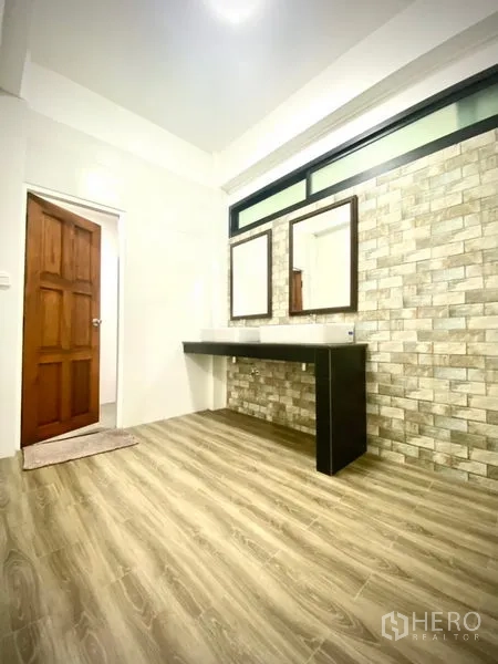 Townhouse for rent in Prawet, Bangkok - Vanity area with twin mirrors and a brick-texture feature wall.