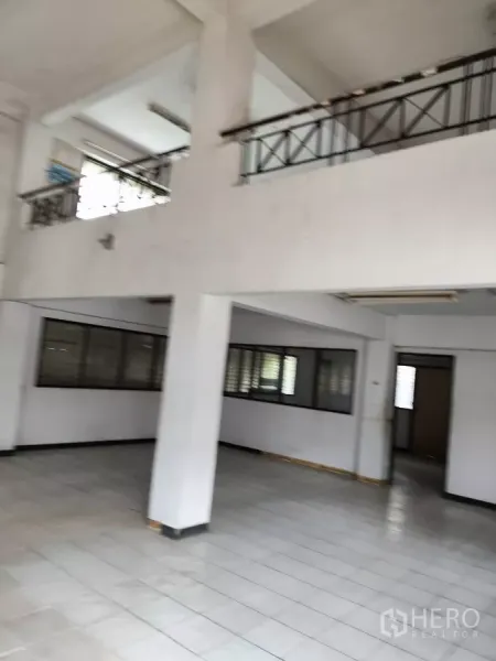 Shophouse for rent in Bueng Kum, Bangkok - Spacious hall with pillars and an upper walkway overlooking the main floor.