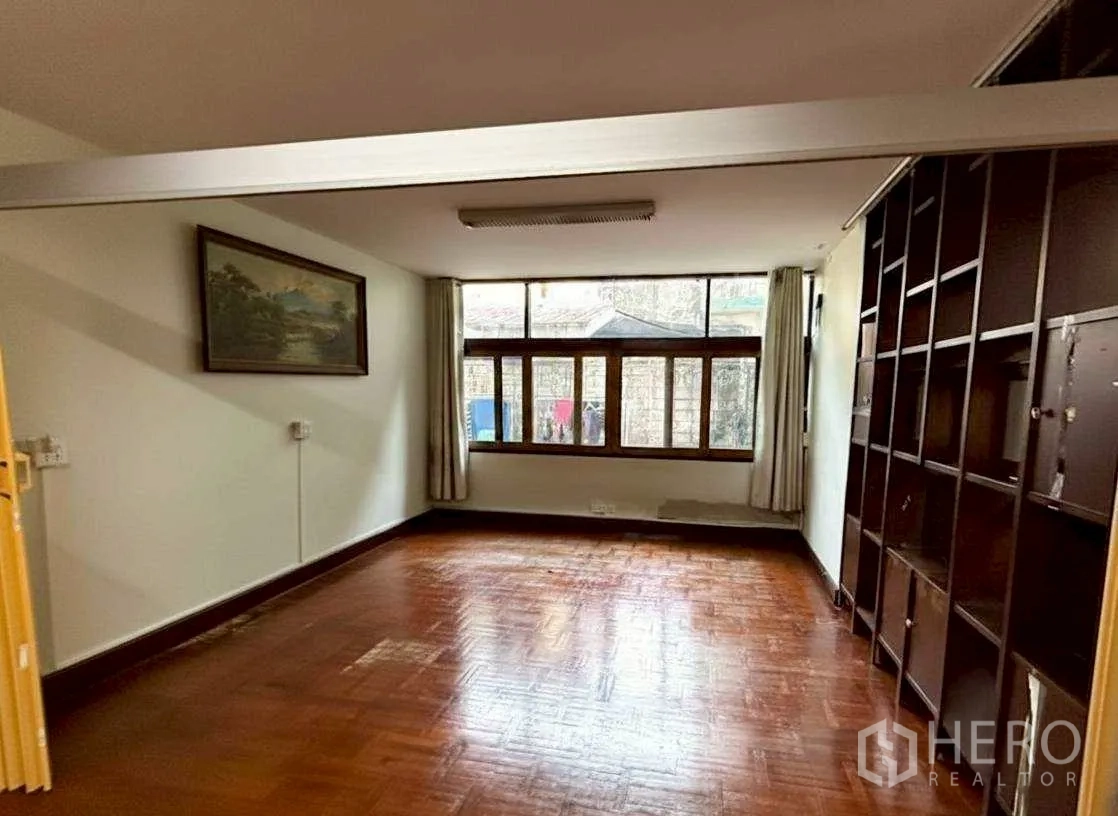Home Office for rent in Bang Rak, Bangkok - Room with wall-to-wall shelving, large window and parquet floor.