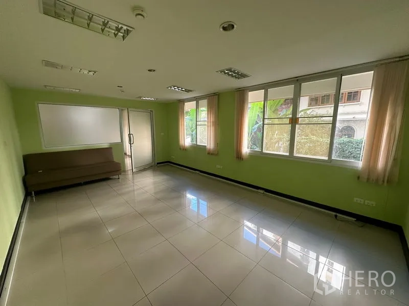 สำนักงาน ขาย - ห้องหัวมุมหน้าต่างบานใหญ่ ผนังสีเขียว กระดานไวท์บอร์ด และประตูกระจก