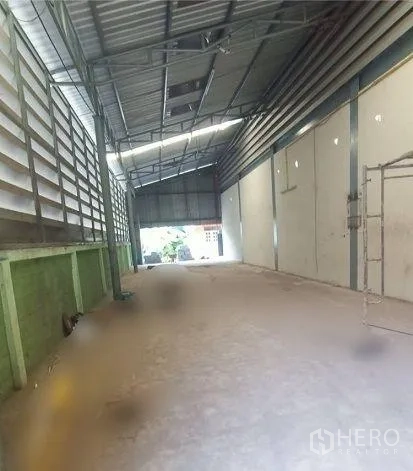 Factory for rent in Mueang Samut Sakhon, Samut Sakhon - Side bay of the factory featuring tall metal cladding, ventilation louvers, and roller-door access.