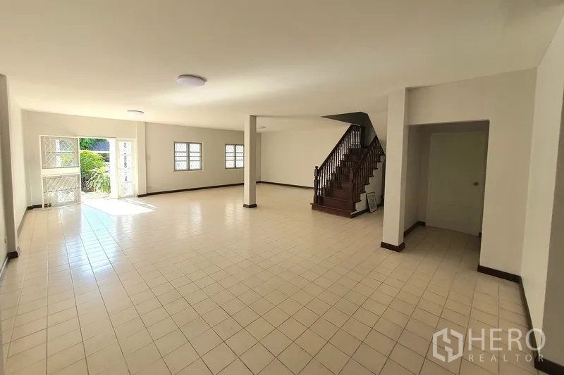 联排别墅 出售在Khlong Toei, Bangkok - 一层超大起居厅，瓷砖地面，多扇窗户与木楼梯。