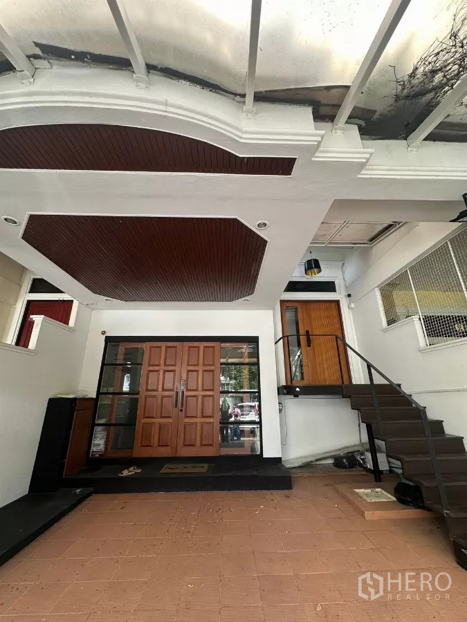 ทาวน์เฮาส์ ให้เช่าในWatthana, Bangkok - โรงจอดรถมีหลังคาปูกระเบื้อง ประตูไม้บานคู่ และบันไดด้านข้าง