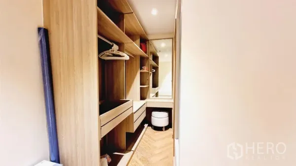 Condominium for sale in Watthana, Bangkok - Walk-in closet with warm wood shelving, drawers and a vanity mirror providing ample storage.