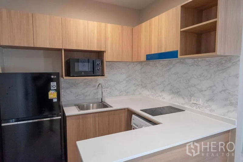 คอนโด ให้เช่าในBang Na, Bangkok - ครัวรูปตัว U ผนังลายหินอ่อน มีเตา ซิงก์ ตู้เย็น และไมโครเวฟ