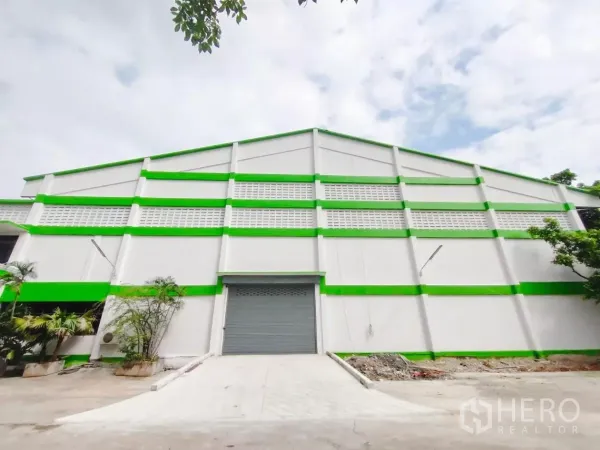 โรงงาน ขายในSamut Prakan - ด้านหน้าโรงงานสีขาวคาดเขียว พร้อมประตูม้วนและทางลาด ในบางเสาธง สมุทรปราการ
