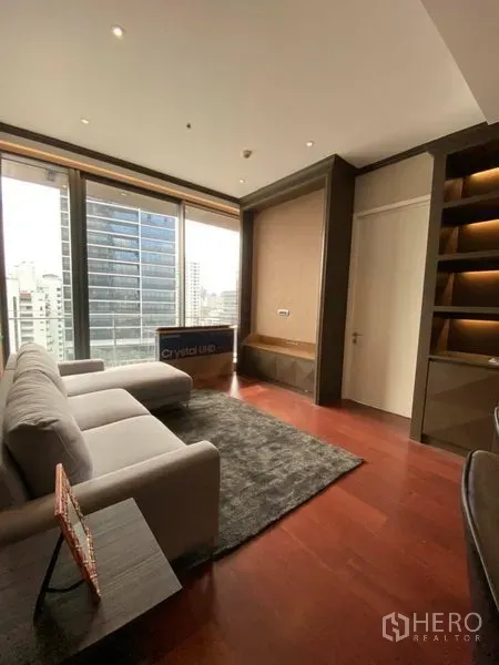 คอนโด ให้เช่าในWatthana, Bangkok - ห้องนั่งเล่นสว่าง โซฟาสีเทา พรม และหน้าต่างเต็มความสูงมองเห็นสกายไลน์กรุงเทพฯ