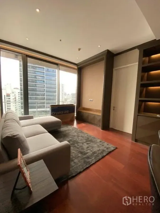 Condominium for rent in Watthana, Bangkok - Bright living room with grey sofa, rug and full-height windows overlooking the Bangkok skyline.