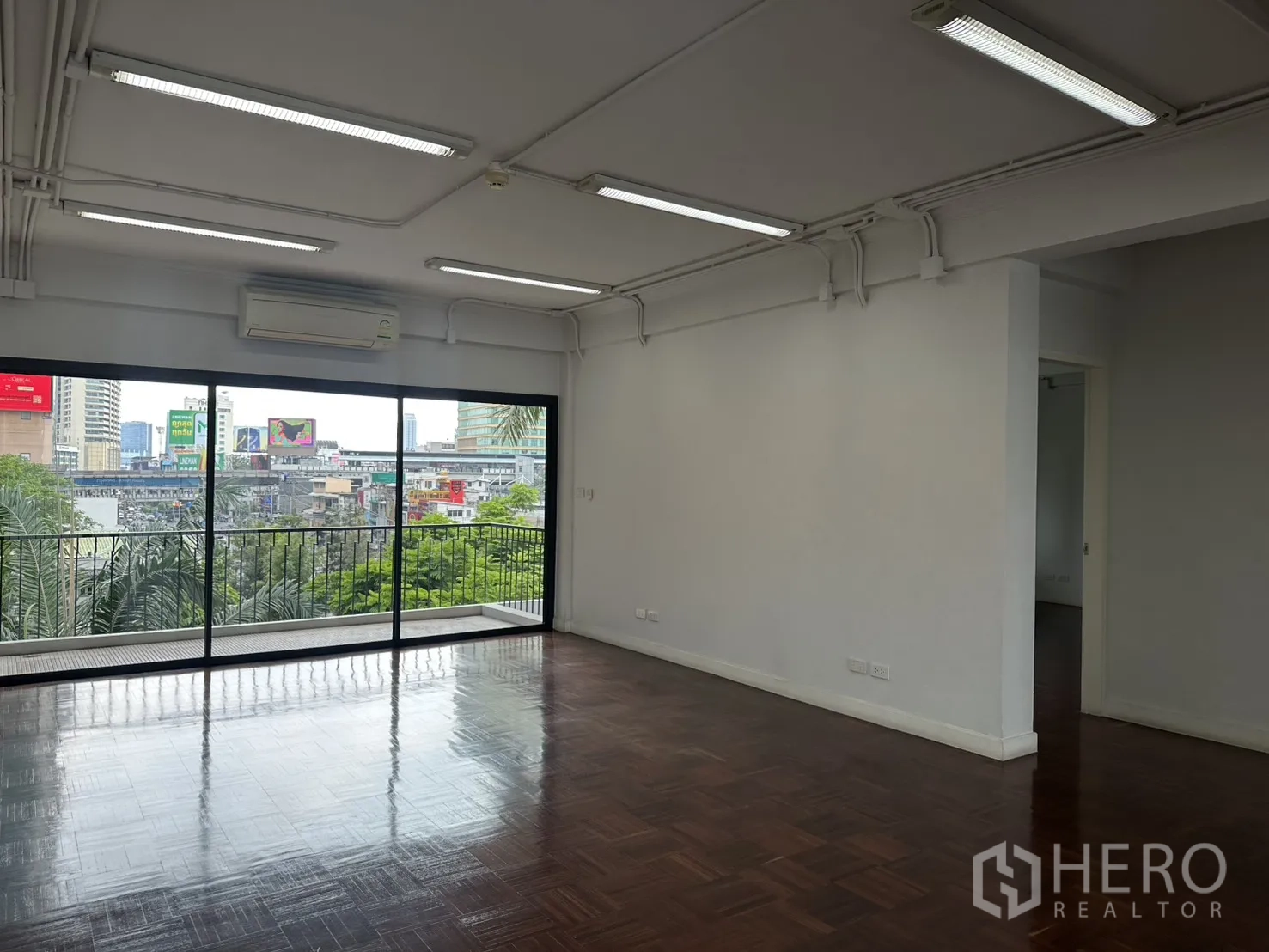 办公室 for rent in Watthana, Bangkok - 开放办公区，推拉玻璃门通向带栏杆的露台，远眺天际线。