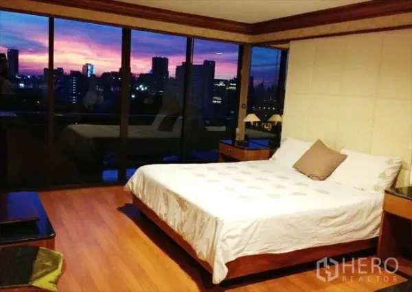 คอนโด ขายในPathum Wan, Bangkok - ห้องนอนใหญ่เตียงคิง พื้นไม้ และหน้าต่างบานสูงชมวิวพระอาทิตย์ตกของเมือง