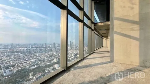 Condominium for sale in Bangkok - Unfinished high-floor corridor with floor-to-ceiling windows and expansive Bangkok city views.