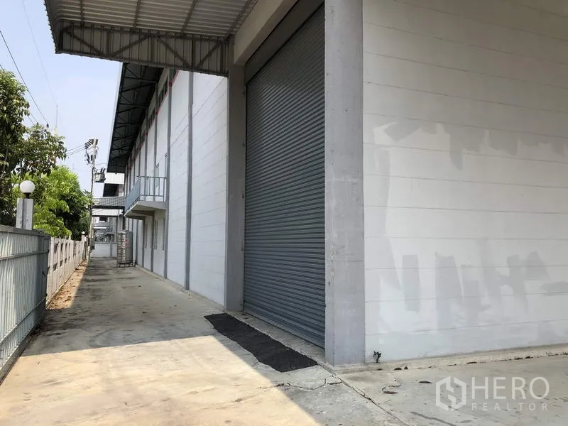 โรงงาน ให้เช่าในLam Luk Ka, Pathum Thani - พื้นที่ขนถ่ายด้านข้างยาว มีประตูม้วนขนาดใหญ่ ชายคาคลุม และรั้วความปลอดภัย
