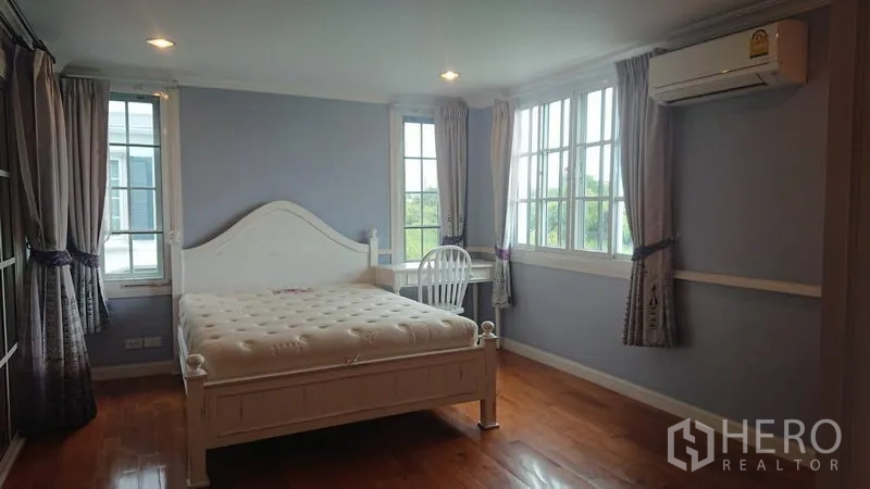 บ้าน ให้เช่าในMueang Samut Prakan, Samut Prakan - ห้องนอนใหญ่โปร่ง เตียงสีขาว พื้นไม้ หน้าต่างรอบด้าน และเครื่องปรับอากาศ