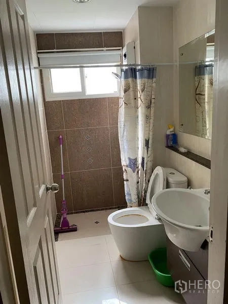 Townhouse for rent in Wang Thonglang, Bangkok - Compact bathroom with toilet, basin, mirror and shower curtain under a window.