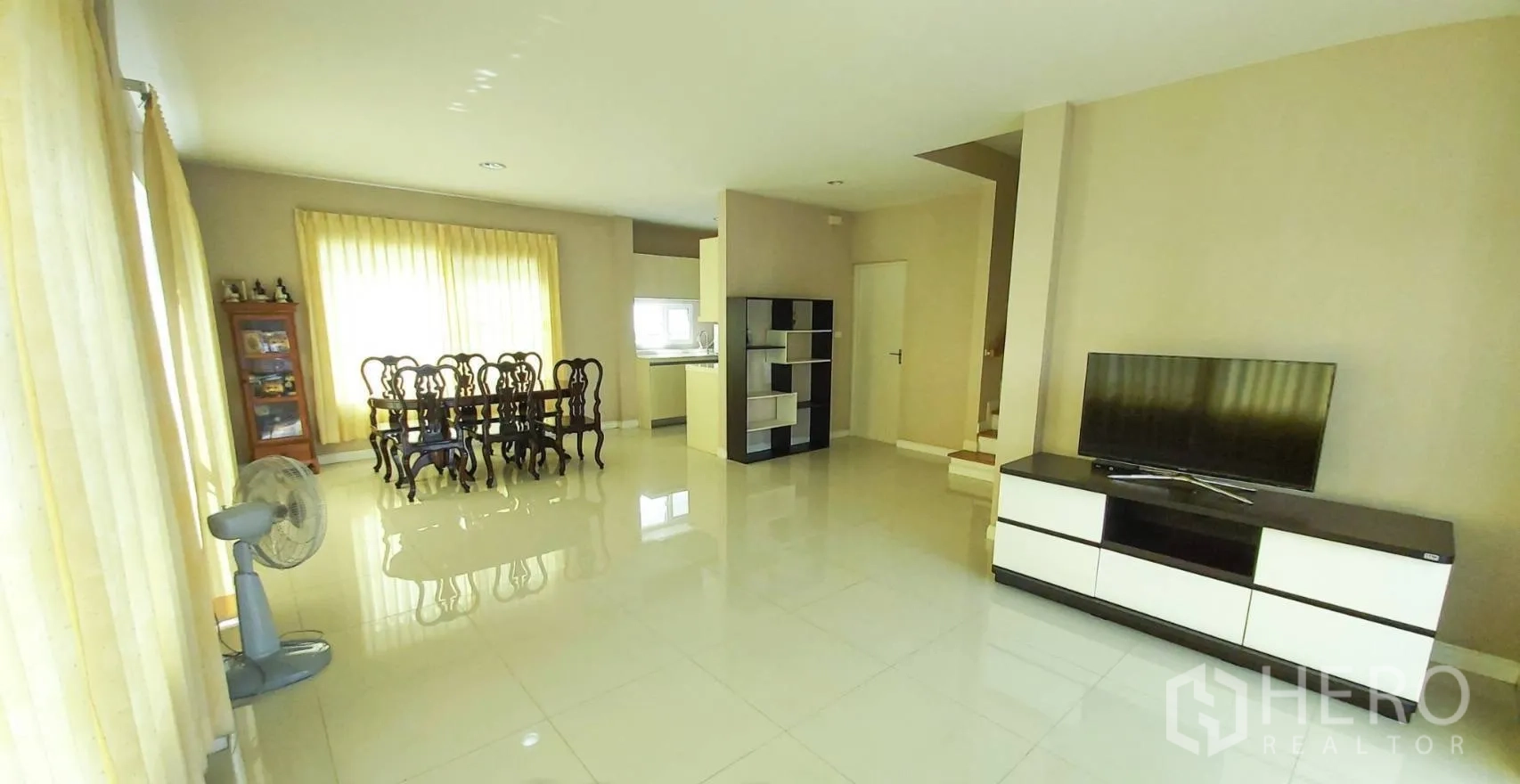 บ้าน for sale in Bang Kapi, Bangkok - ห้องนั่งเล่นกว้าง พร้อมชั้นวางทีวีและชุดโต๊ะอาหาร ข้างหน้าต่างสูงเต็มบาน