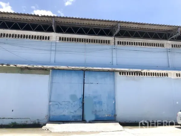 คลังสินค้า ให้เช่าในBang Phli, Samut Prakan - ด้านหน้าโกดังสีฟ้า ประตูเหล็กสไลด์ขนาดใหญ่ พร้อมช่องระบายอากาศใต้ชายคา