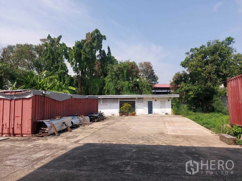 Warehouse for rent in Min Buri, Bangkok - Open storage yard with shipping containers, expansive concrete hardstand and trees along the boundary.