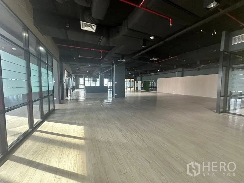 Office Space for rent in Bang Rak, Bangkok - Wide open office floor with multiple window lines bringing daylight across wooden floors.