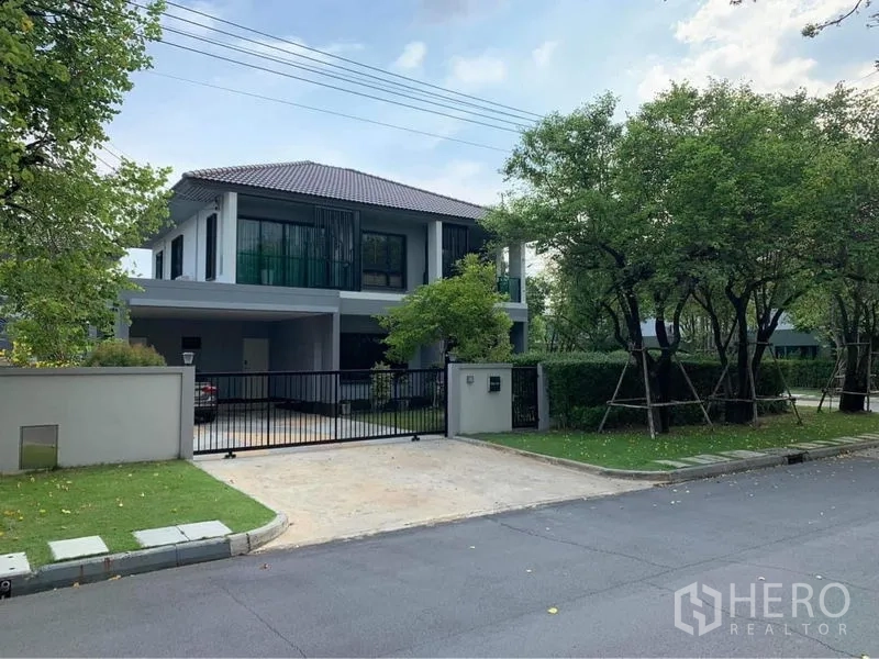 Detached House for rent or sale in Bang Phli, Samut Prakan - Gated entrance and driveway of the detached home on a quiet tree-lined street.