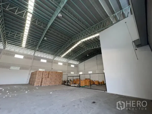คลังสินค้า ให้เช่าในLat Krabang, Bangkok - มุมภายในโกดังที่มีลังสินค้าซ้อนและโซนเก็บของกั้นตาข่ายใต้เพดานสูง