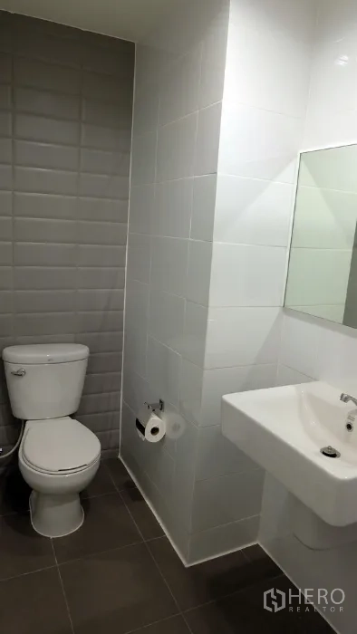 คอนโด ให้เช่าหรือขายในKhlong Toei, Bangkok - ห้องน้ำคอนโดสไตล์โมเดิร์น พร้อมอ่างล้างหน้า กระจก และโถสุขภัณฑ์ ข้างผนังกระเบื้องสีเทา