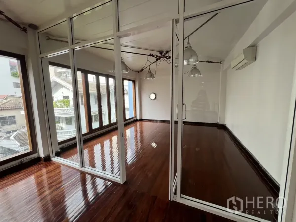 สำนักงานที่บ้าน ให้เช่าในWatthana, Bangkok - ห้องประชุมกั้นกระจกพร้อมหน้าต่างเต็มผนังและพื้นไม้เงางามในตัวอาคาร.