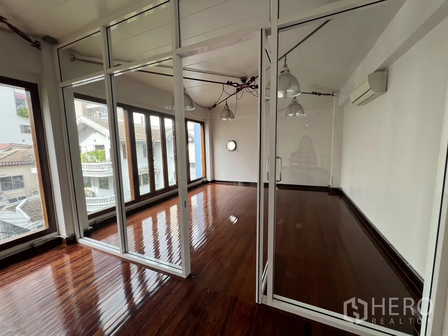 สำนักงานที่บ้าน ให้เช่าในWatthana, Bangkok - ห้องประชุมกั้นกระจกพร้อมหน้าต่างเต็มผนังและพื้นไม้เงางามในตัวอาคาร.