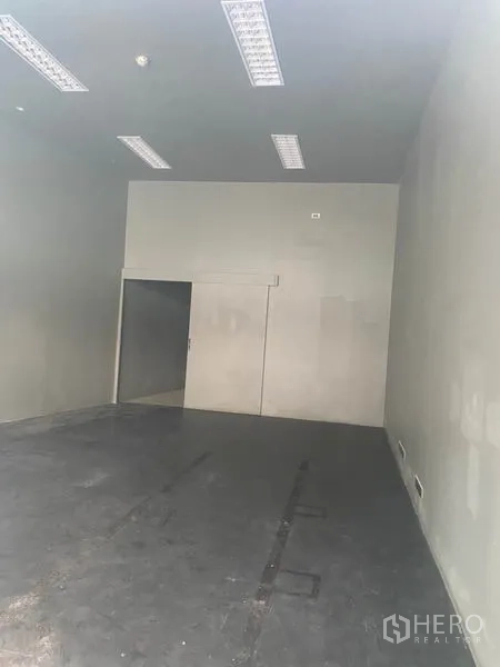 零售空间 出租在Khlong Toei, Bangkok - 空置商铺内部，高挑层高、荧光灯与水泥地面。