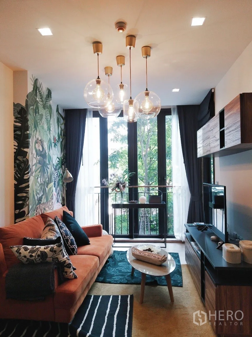 公寓 for rent in Watthana, Bangkok - 温馨客厅，球形吊灯、沙发与花园绿景。